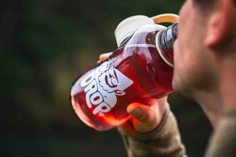 Persona tomando jugo de frambuesa DropCo al aire libre