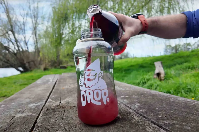 Jugo de frambuesa concentrado DropCo servido en una botella al aire libre